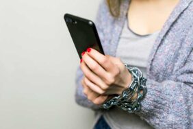 Teen Girl with chain locked hands using a smartphone isolated on white background